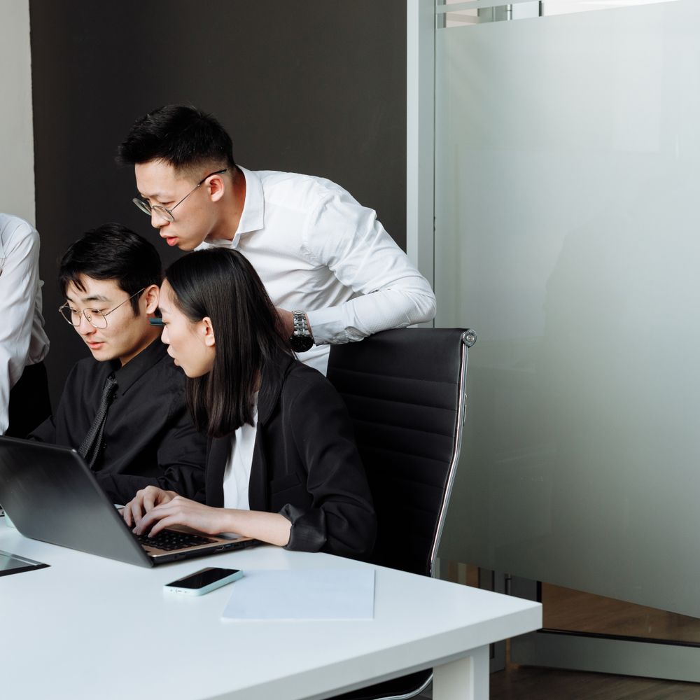 A team collaborating around a laptop in a modern office, representing business growth
